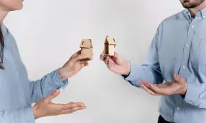 Rozdzielność majątkowa a wspólny dom: dwoje ludzi trzyma miniaturowe domki, symbolizujące podział majątku.