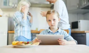 Smutna dziewczynka z tabletem w ręku, podczas gdy rodzice się kłócą. Długo trwa sprawa o pozbawienie praw rodzicielskich.