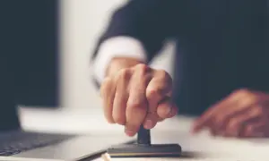 Dłoń z pieczątką, symbolizująca finalizację formalności po uzyskaniu aktu poświadczenia dziedziczenia. Co dalej?