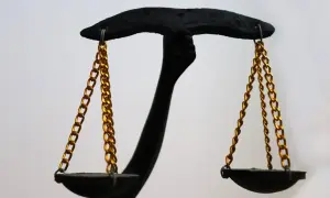 Czarna waga z złotymi łańcuszkami symbolizuje rozważania: czy warto być opiekunem prawnym?