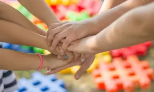 Dzieci łączą dłonie, symbolizując jedność. Kto to ojczym? To ten, kto wspiera i buduje rodzinę, jak te kolorowe klocki.