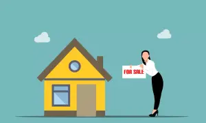 Kobieta z tabliczką "FOR SALE" przy żółtym domu. Szybka sprzedaż mieszkania przed upływem 5 lat.