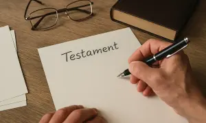 Ręka pisze piórem na dokumencie "Testament". Obok leżą okulary i księga. Czy testament można zmienić? Tak, można.
