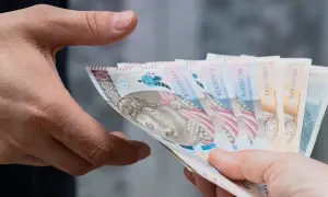 Dwie dłonie przekazują sobie plik banknotów. Zastanawiasz się, ile bank zabiera po śmierci?