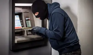 Złodziej w kominiarce i rękawiczkach wyciąga pieniądze z bankomatu. Czy bank odda skradzione pieniądze z konta?