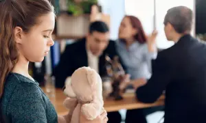 Smutna dziewczynka z misiem w tle kłócący się rodzice. Czy matka może wyprowadzić się z dzieckiem bez zgody ojca?