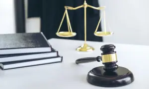 Młotek sędziowski, waga sprawiedliwości i stos ksiąg symbolizują ważną decyzję, jaką jest odrzucenie spadku u notariusza.