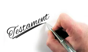 Dłoń pisze długopisem słowo "Testament". To ważny wzór testamentu własnoręcznego.