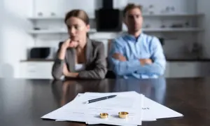 Para rozwodzi się, na stole dokumenty i obrączki. Argumenty do rozwodu są widoczne na papierach.