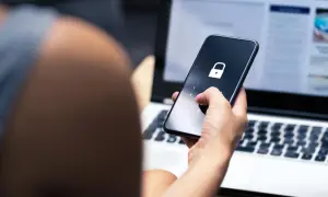 Dłoń z różowym lakierem wpisuje kod na telefonie z ikoną kłódki. To może być pierwszy krok, jak sprawdzić czy ktoś ma kredyt, gdy dane są chronione.