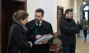 Prawnik w todze omawia dokumenty z kobietą, podczas gdy mężczyzna w kurtce czeka. Sprawa dotyczy artykułu 109 KRIO.