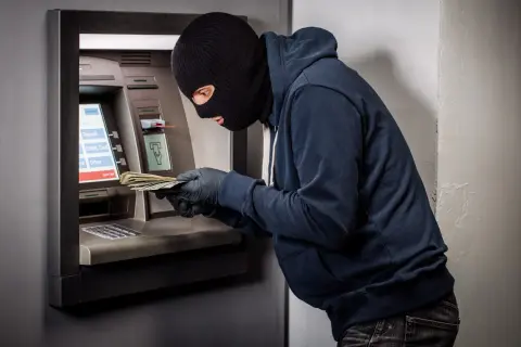 Złodziej w kominiarce i rękawiczkach wyciąga pieniądze z bankomatu. Czy bank odda skradzione pieniądze z konta?