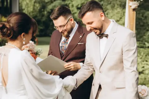 Uroczystość ślubu cywilnego, podczas której para młoda wymienia obrączki. W tle urzędnik udzielający ślubu.