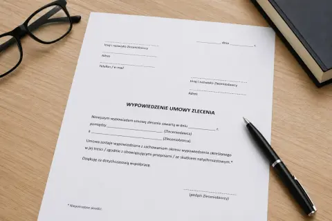 Dokument "Wypowiedzenie umowy zlecenia" leży na drewnianym biurku obok okularów i długopisu.