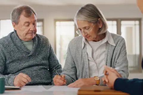 Starsza para podpisuje dokumenty. Zastanawiają się, kiedy umowa dożywocia jest nieważna, szukając porady prawnej.