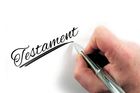 Dłoń pisze długopisem słowo "Testament". To ważny wzór testamentu własnoręcznego.