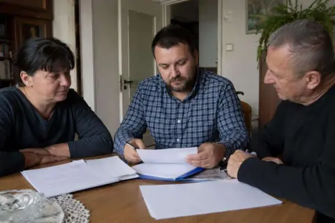 Rodzina przy stole omawia dokumenty. Czy u notariusza muszą być wszyscy spadkobiercy?