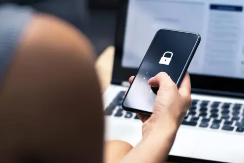 Dłoń z różowym lakierem wpisuje kod na telefonie z ikoną kłódki. To może być pierwszy krok, jak sprawdzić czy ktoś ma kredyt, gdy dane są chronione.