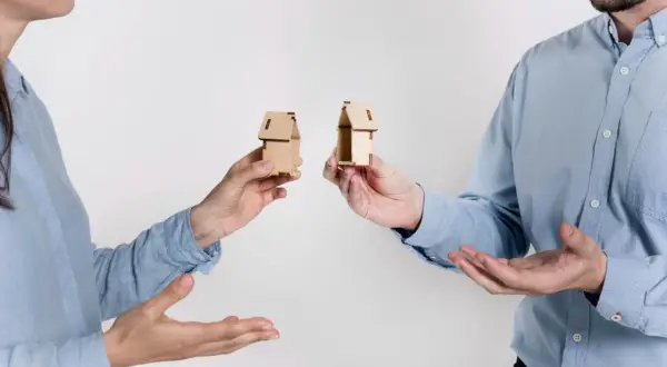 Rozdzielność majątkowa a wspólny dom: dwoje ludzi trzyma miniaturowe domki, symbolizujące podział majątku.