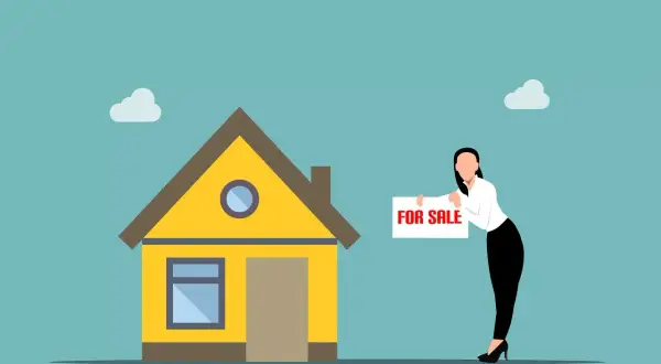 Kobieta z tabliczką "FOR SALE" przy żółtym domu. Szybka sprzedaż mieszkania przed upływem 5 lat.