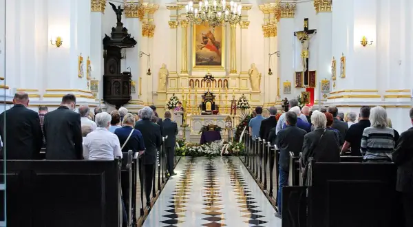Uroczystość pogrzebowa w kościele. Rodzina i przyjaciele żegnają zmarłego. Warto pamiętać o zasiłku pogrzebowym i zwrocie kosztów pogrzebu z banku.
