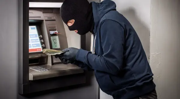 Złodziej w kominiarce i rękawiczkach wyciąga pieniądze z bankomatu. Czy bank odda skradzione pieniądze z konta?