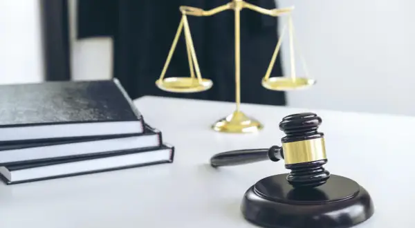 Młotek sędziowski, waga sprawiedliwości i stos ksiąg symbolizują ważną decyzję, jaką jest odrzucenie spadku u notariusza.