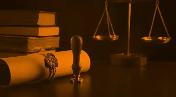 Zapieczętowany dokument, waga sprawiedliwości i księgi symbolizują ostatnią wolę zmarłego.