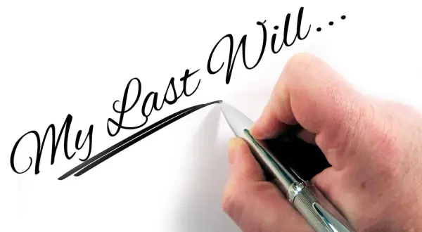 Dłoń pisze długopisem "My Last Will...", myśląc o przyszłości dzieci i testament wzajemny.