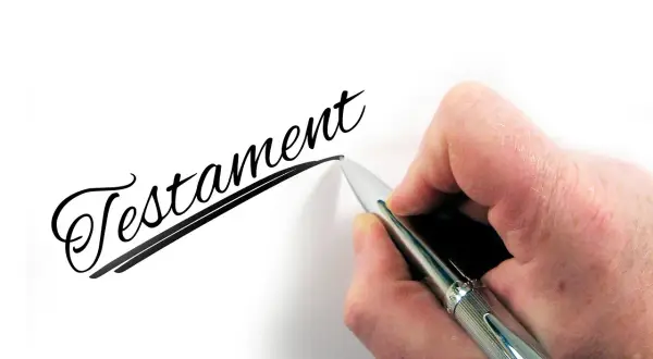 Dłoń pisze długopisem słowo "Testament". To ważny wzór testamentu własnoręcznego.