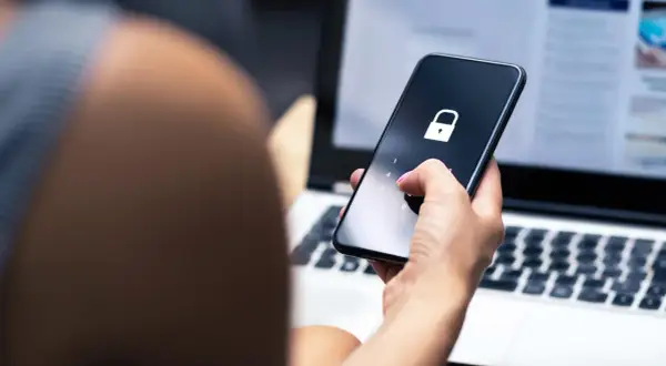 Dłoń z różowym lakierem wpisuje kod na telefonie z ikoną kłódki. To może być pierwszy krok, jak sprawdzić czy ktoś ma kredyt, gdy dane są chronione.