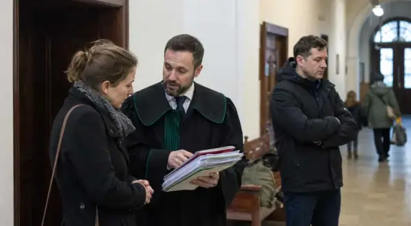 Prawnik w todze omawia dokumenty z kobietą, podczas gdy mężczyzna w kurtce czeka. Sprawa dotyczy artykułu 109 KRIO.