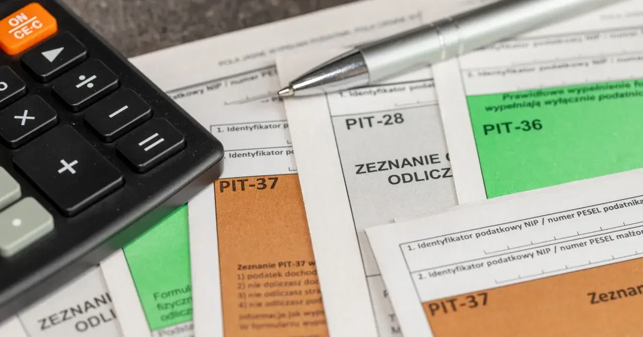 Kalkulator i długopis leżą na dokumentach PIT-37, PIT-28 i PIT-36. Czas na rozliczenie podatku i skorzystanie z ulg, czyli ikze odliczenie od podatku.