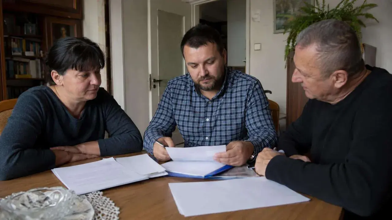 Rodzina przy stole omawia dokumenty. Czy u notariusza muszą być wszyscy spadkobiercy?