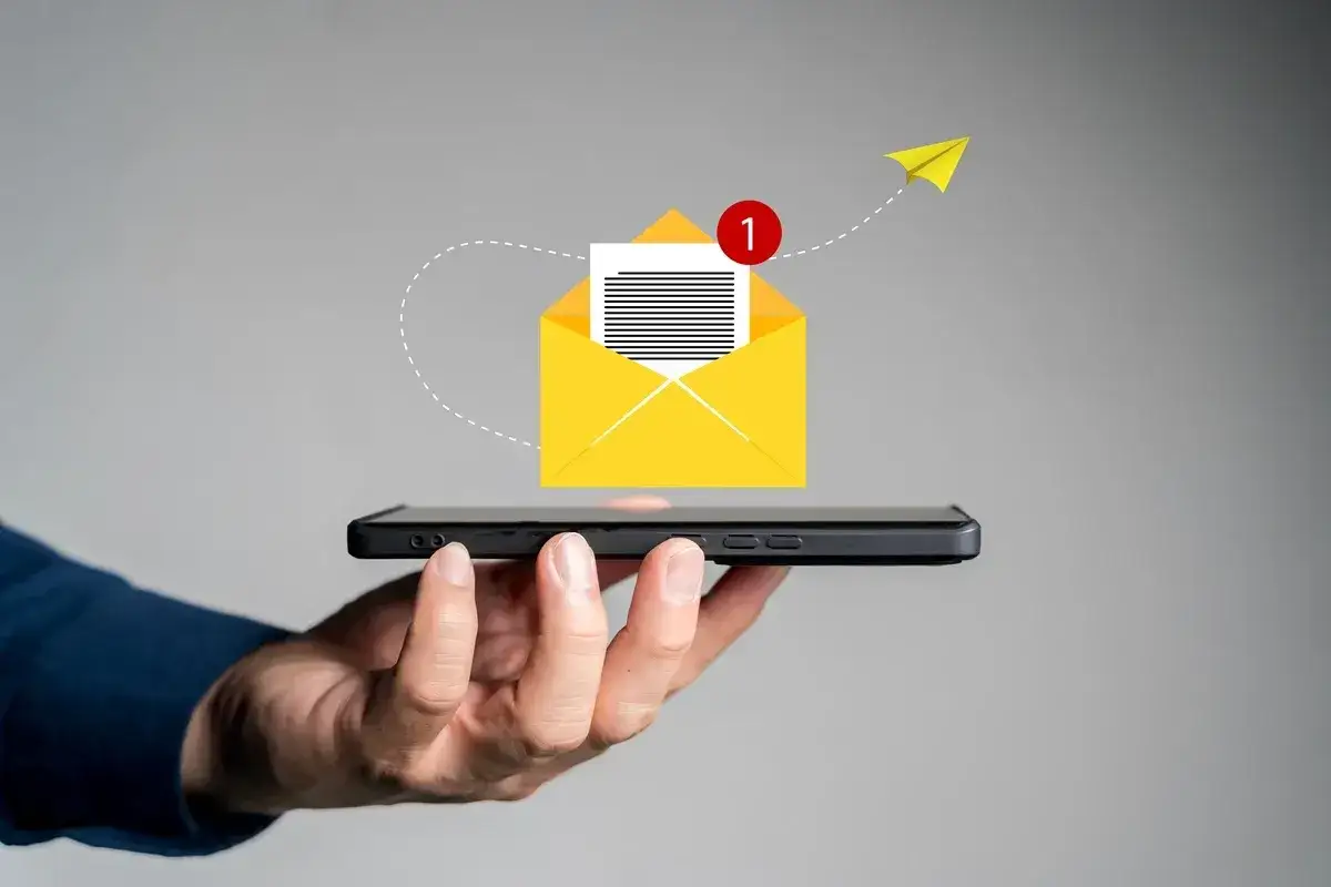 Telefon z otwartą kopertą i powiadomieniem o nowej wiadomości. W tle papierowy samolot symbolizujący szybką komunikację, jak urlop na żądanie sms.