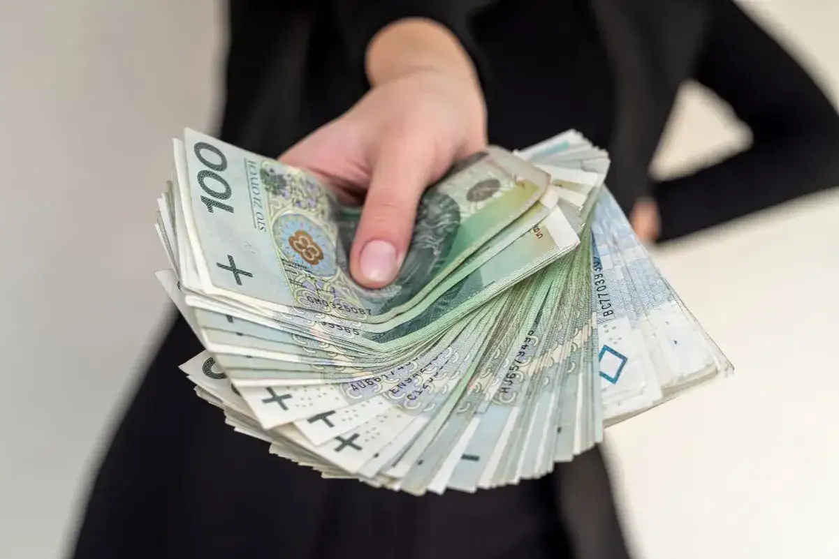 Dłoń trzymająca plik banknotów 100 zł. Takie sytuacje mogą być przykładami rażącej niewdzięczności, gdy pomoc finansowa nie jest doceniana.