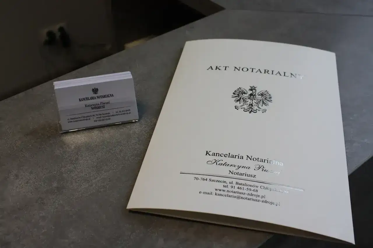 Akt notarialny i wizytówka kancelarii notarialnej Katarzyny Piwoni. Dokument może dotyczyć rozszerzenia wspólności majątkowej.