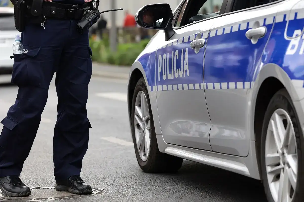 Policjant stoi obok radiowozu. Czy policjant może mnie przeszukać na ulicy? To zależy od sytuacji i podstaw prawnych.