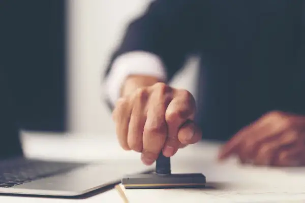 Dłoń z pieczątką, symbolizująca finalizację formalności po uzyskaniu aktu poświadczenia dziedziczenia. Co dalej?