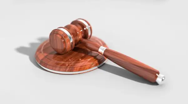 Drewniany młotek sędziowski na tle, symbol sprawiedliwości i testamentu.
