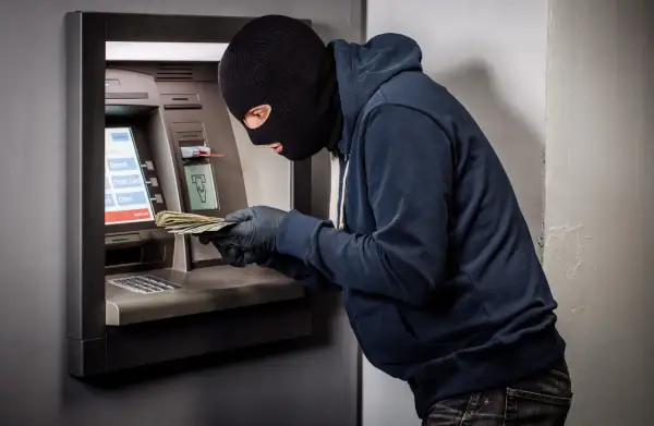 Złodziej w kominiarce i rękawiczkach wyciąga pieniądze z bankomatu. Czy bank odda skradzione pieniądze z konta?