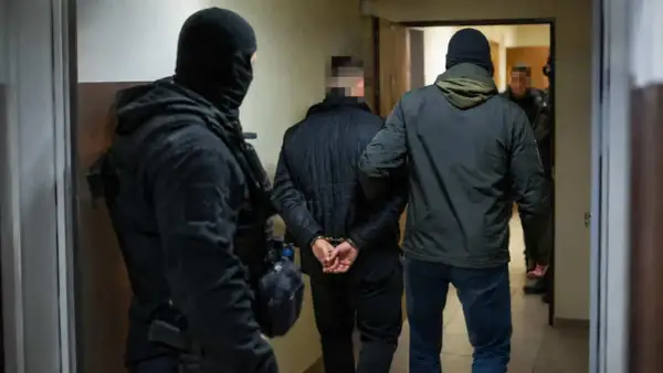 Funkcjonariusze zatrzymują podejrzanego, który jest częścią zorganizowanej grupy przestępczej. Mężczyzna ma założone kajdanki.