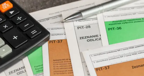 Kalkulator i długopis leżą na dokumentach PIT-37, PIT-28 i PIT-36. Czas na rozliczenie podatku i skorzystanie z ulg, czyli ikze odliczenie od podatku.