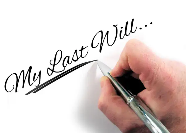 Dłoń pisze długopisem "My Last Will...", myśląc o przyszłości dzieci i testament wzajemny.