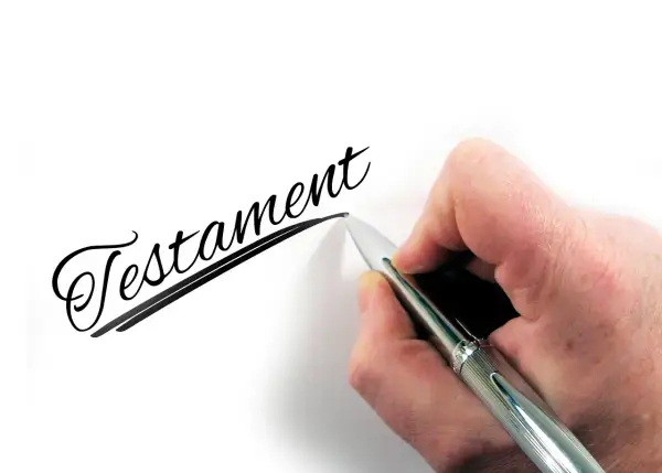 Dłoń pisze długopisem słowo "Testament". To ważny wzór testamentu własnoręcznego.