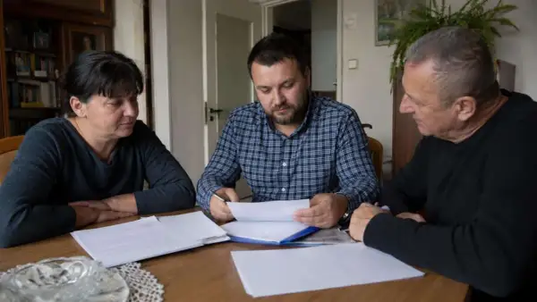 Rodzina przy stole omawia dokumenty. Czy u notariusza muszą być wszyscy spadkobiercy?