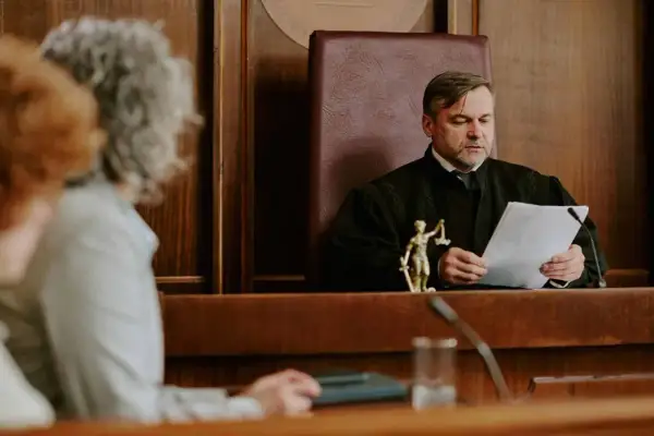 Sędzia w todze analizuje dokumenty, zastanawiając się, jakie pytania zadać na rozprawie o ograniczenie praw rodzicielskich.