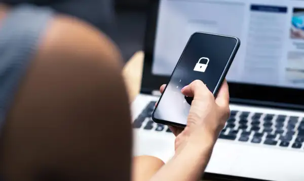 Dłoń z różowym lakierem wpisuje kod na telefonie z ikoną kłódki. To może być pierwszy krok, jak sprawdzić czy ktoś ma kredyt, gdy dane są chronione.